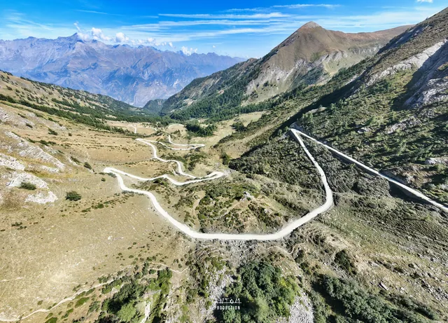 Vallée alpine et route en lacets vues par drone sous un ciel bleu