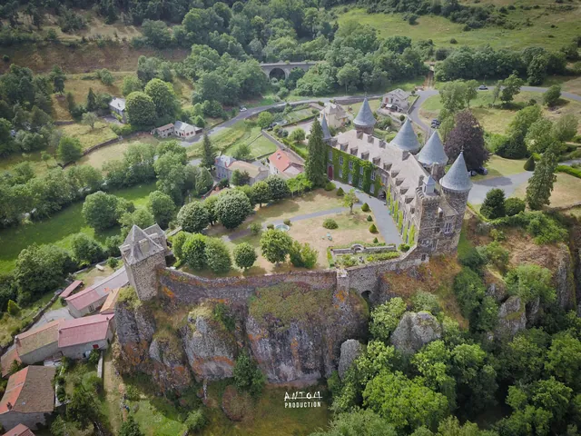Château aux toits en poivrière dominant un village auvergnat, vue aérienne par drone