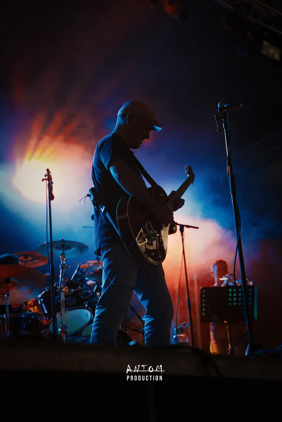 Guitariste sur scène dans un halo de fumée orange et bleue